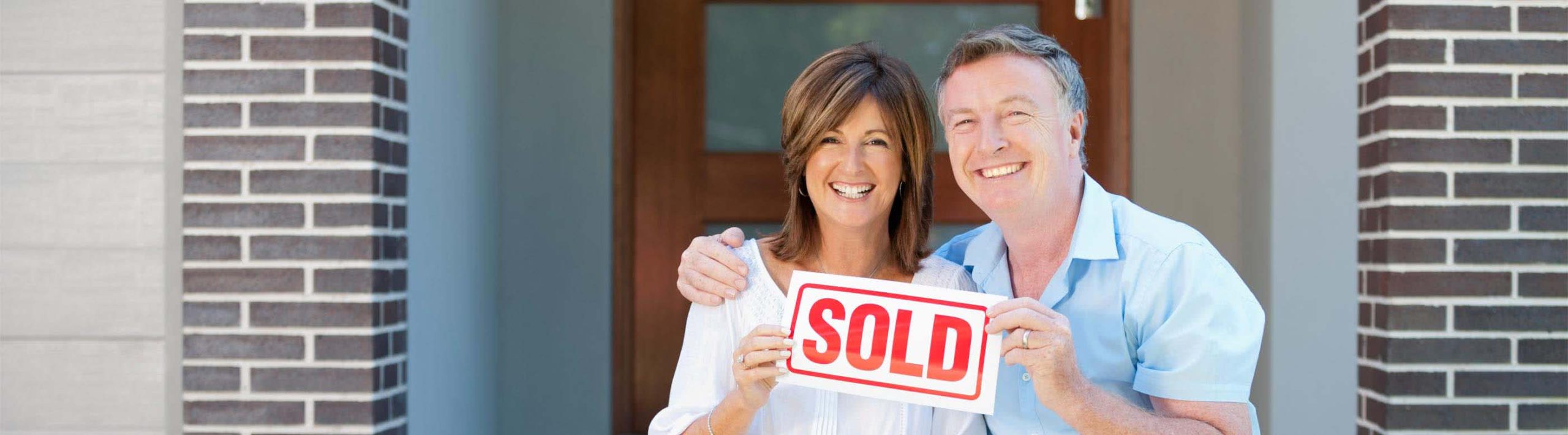 happy couple holding sold sign